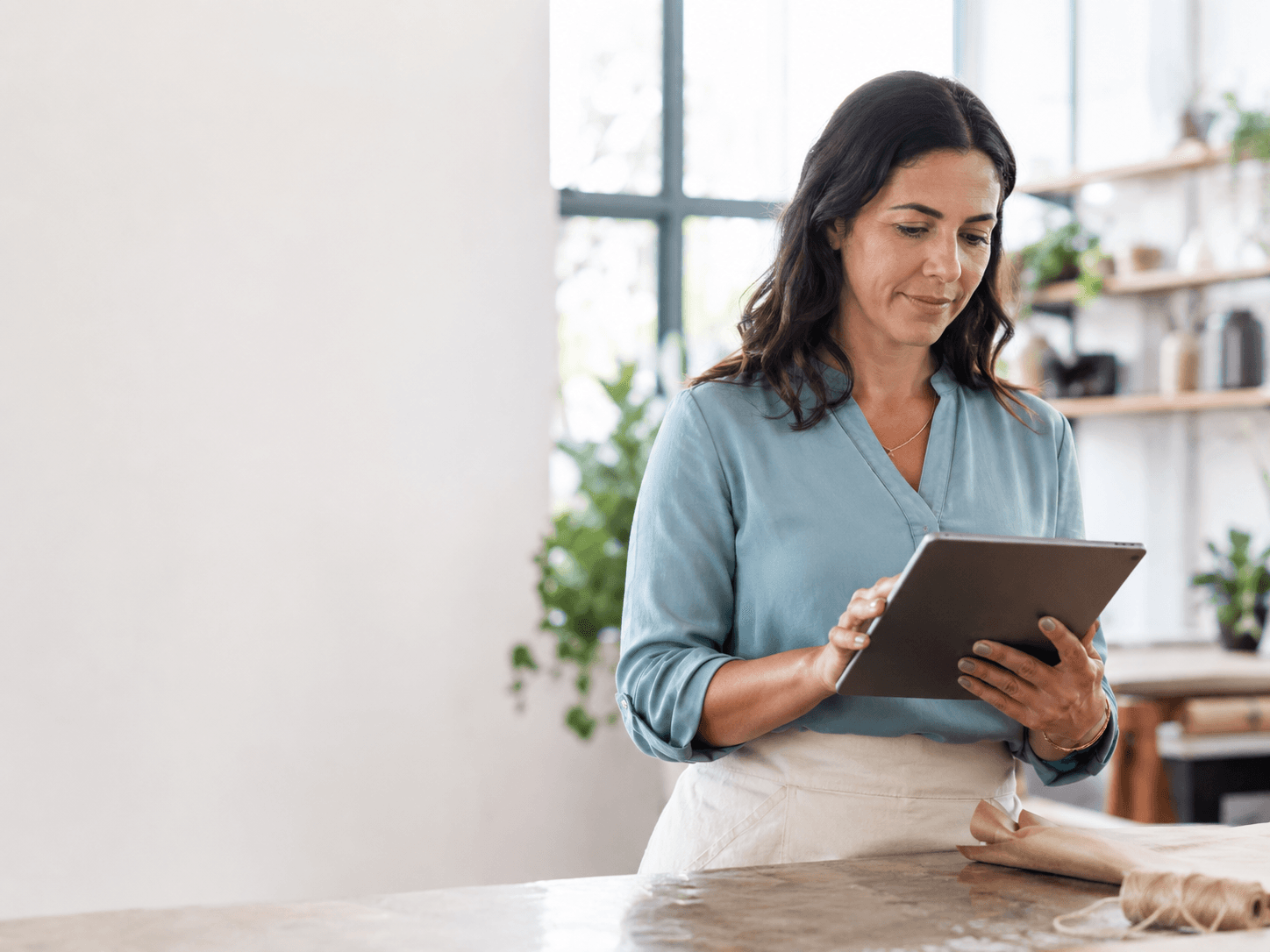 Business owner reviewing leads on a tablet at a bright workspace counter